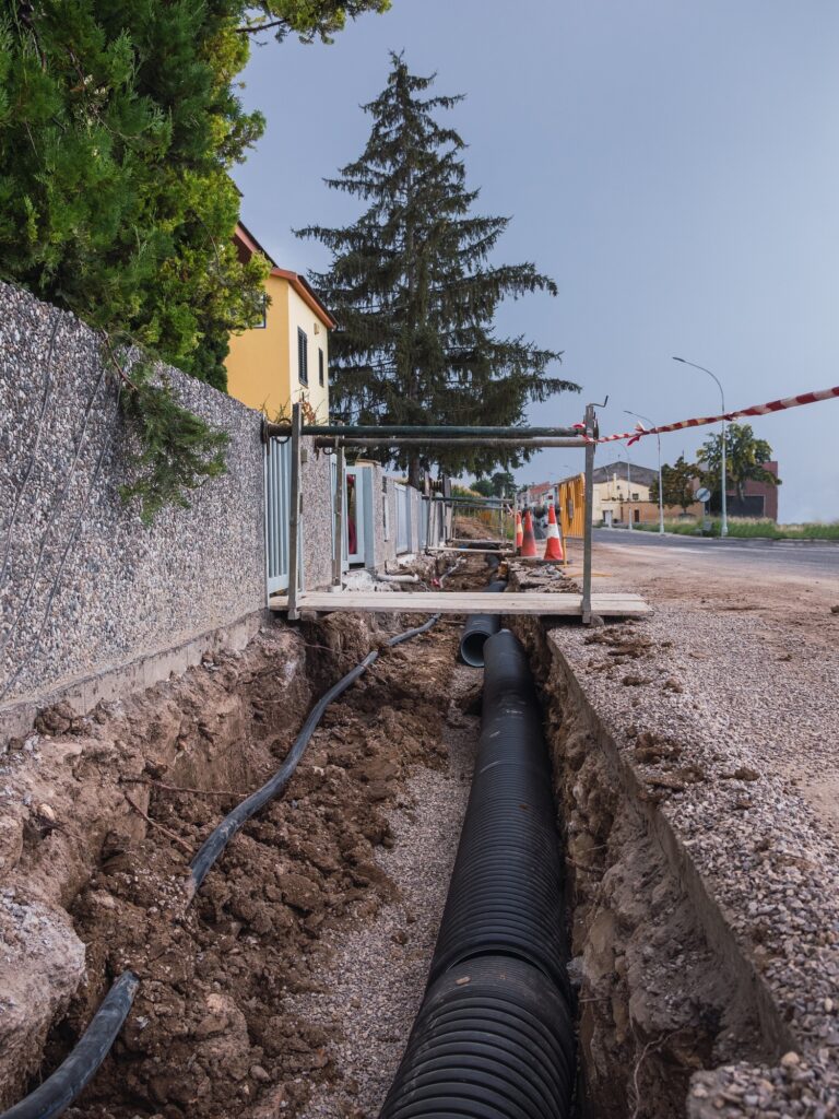 Zanja con nuevas tuberías de agua en el suelo de una calle residencial - Concepto de obra pública